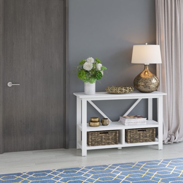 A white sidetable sits next to a brown door.