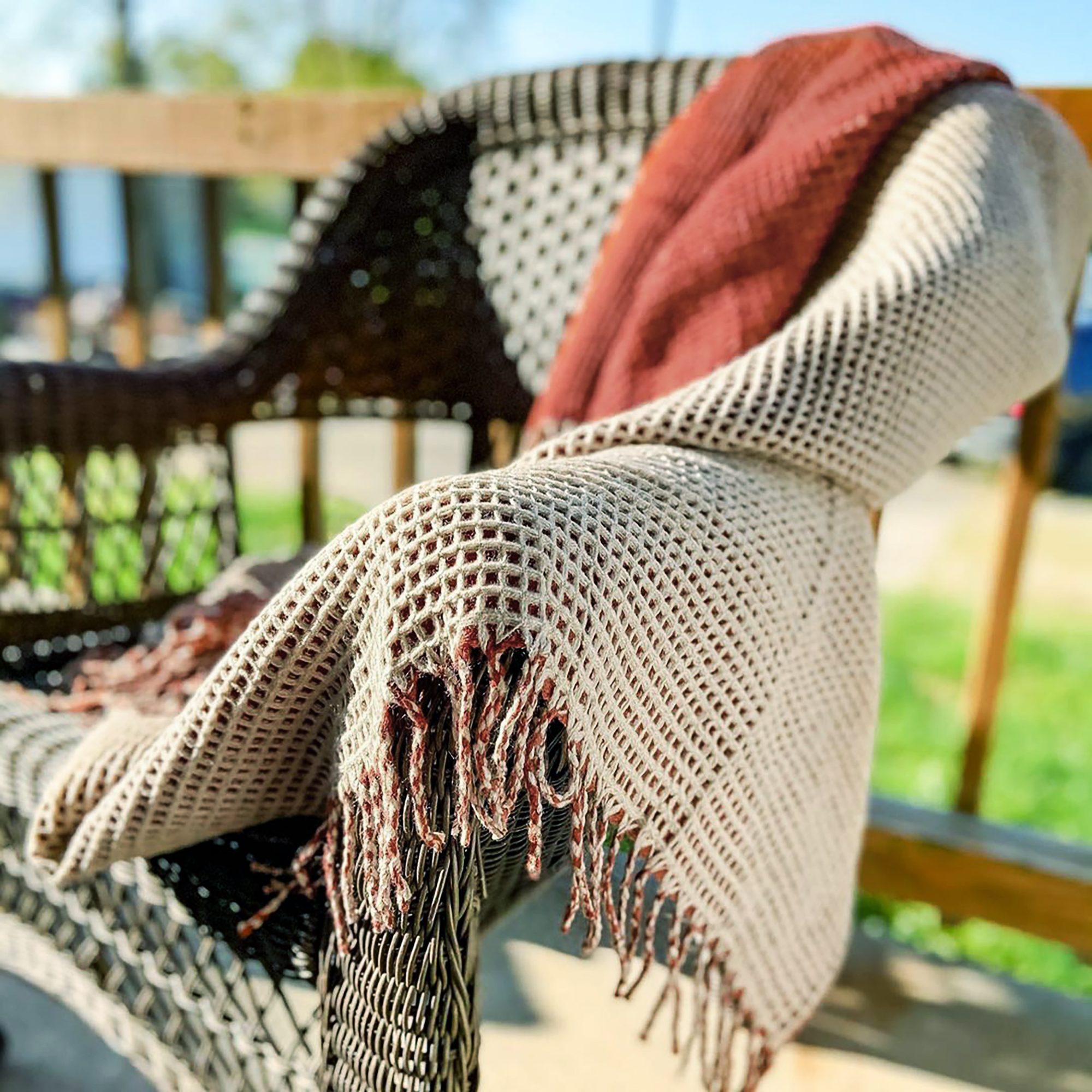 Earth-toned throw blankets are draped over a wicker chair.